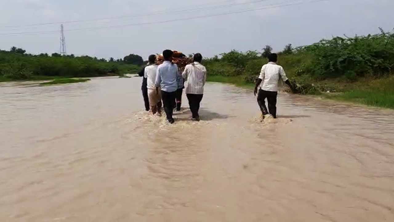 ಅಂತ್ಯಕ್ರಿಯೆ ಹೆಣಗಾಟ: ನೀರಿನ ಮಧ್ಯೆಯೇ ಶವ ಸಾಗಿಸಲು ಕುಟುಂಬಸ್ಥರ ಪರದಾಟ