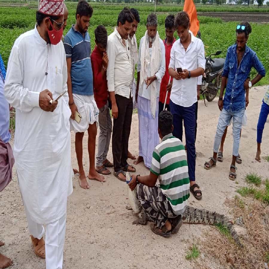 ಮೊಸಳೆ ಹಿಡಿದ ವೇಷಗಾರ ಮಲ್ಲಯ್ಯನ ಜೊತೆ ಮೊಸಳೆ ಕಂಡ ಖುಷಿಯಲ್ಲಿ ಫೋಟೋ ತೆಗೆದುಕೊಳ್ಳುತ್ತಿರುವ ಗ್ರಾಮಸ್ಥರು.