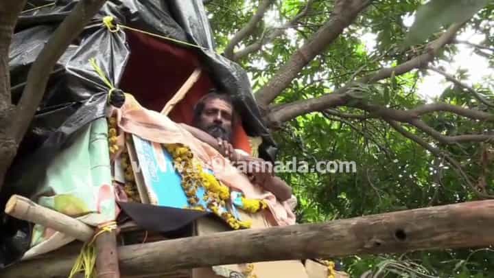 ಕೊಪ್ಪಳ: 5 ದಿನಗಳಿಂದ ಮರದ ಮೇಲೆ ಕುಳಿತು ಸ್ವಾಮೀಜಿ ವ್ರತ! 101 ದಿನ ಮರದಲ್ಲೇ ಇರಲಿರುವ ಸಚ್ಚಿದಾನಂದ ಶ್ರೀ ಕೊಪ್ಪಳ: 5 ದಿನಗಳಿಂದ ಮರದ ಮೇಲೆ ಕುಳಿತು ಸ್ವಾಮೀಜಿ ವ್ರತ! 101 ದಿನ ಮರದಲ್ಲೇ ಇರಲಿರುವ ಸಚ್ಚಿದಾನಂದ ಶ್ರೀ