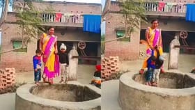 ಬಾವಿ ಕಟ್ಟೆ ಹತ್ತಿ ಎರಡೂ ಕೈಗಳಲ್ಲೂ ಮಕ್ಕಳನ್ನು ಹಿಡಿದು ಮಹಿಳೆಯ ನೃತ್ಯ