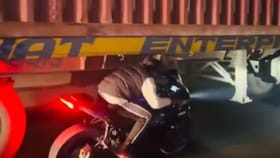 ಚಲಿಸುತ್ತಿರುವ ಟ್ರಕ್​ನಡಿ ಬೈಕ್ ಓಡಿಸಿದ ವ್ಯಕ್ತಿ